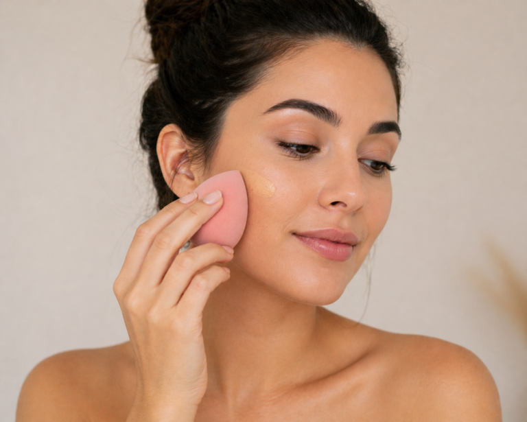 Woman applying liquid foundation with a beauty sponge for a smooth, natural finish