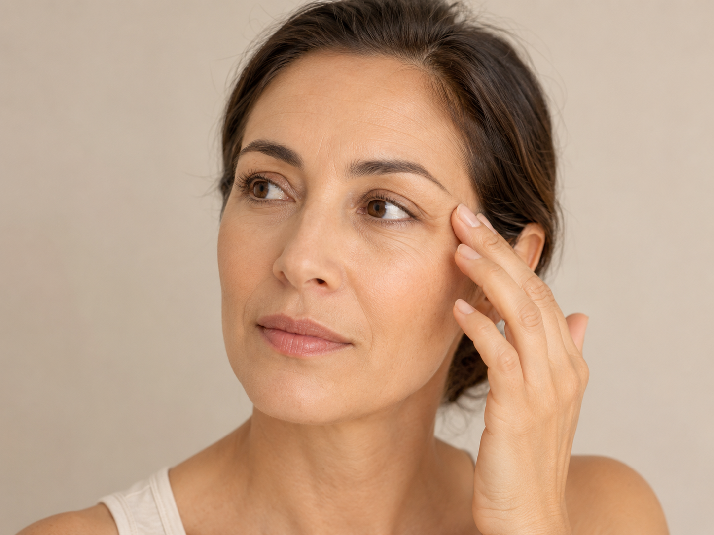 Woman touching fine lines on her face for an article about retinal for skin